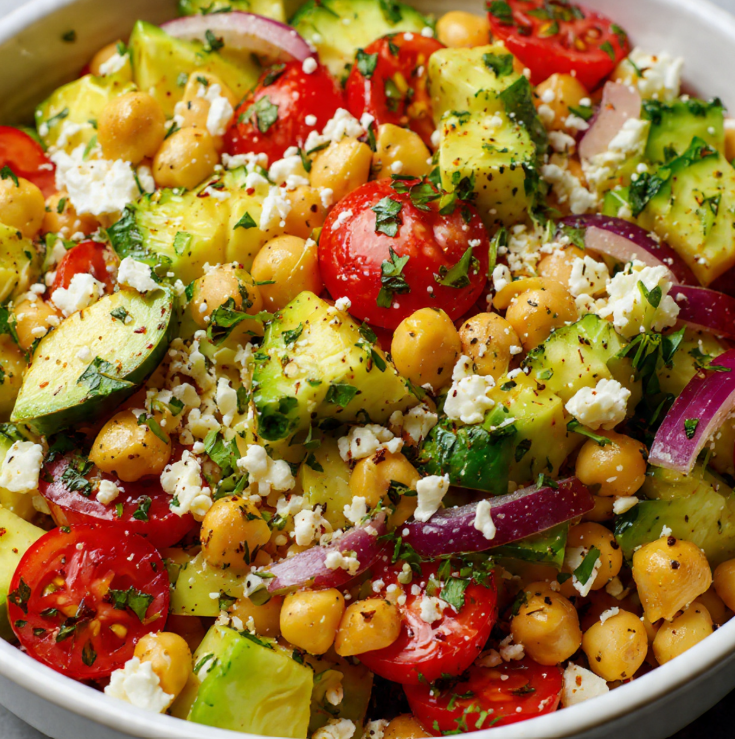 Close-up of creamy avocado chunks mixed with chickpeas, feta, and fresh vegetables