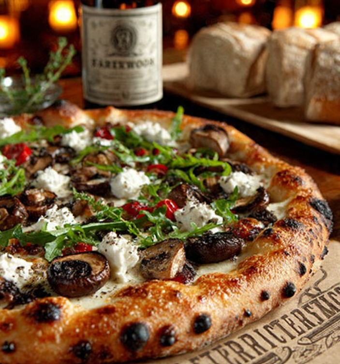 Artisan truffle mushroom and goat cheese pizza with mixed wild mushrooms, creamy goat cheese crumbles, fresh arugula, and truffle oil drizzle